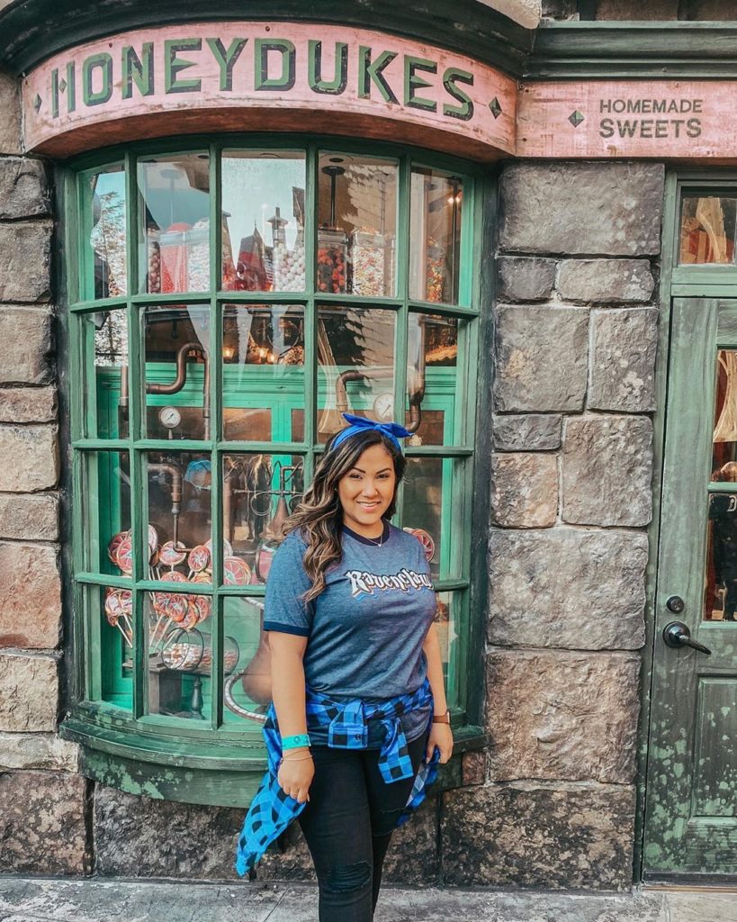 A girl standing in front of Honeydukes in Hogsmeade Village