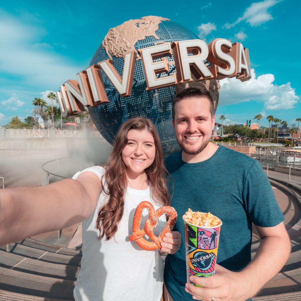 A man and woman in front of the Universal Orlando Resort globe