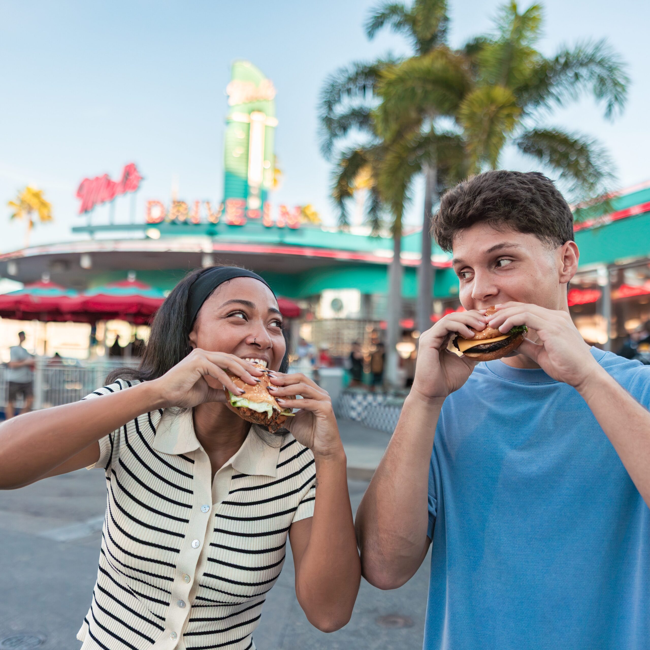A man and woman eating food in front of Mel's Drive-In at Universal Studios Florida